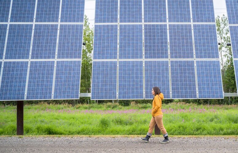 Person walking in front of solar panels
